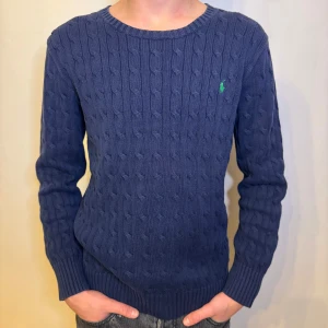 Marinblå Kabelstickad tröja Ralph Lauren - En tvärfet Ralph Lauren kabelstickad tröja | skick 9/10 | storlek 18-20/XL i barnstorlek, motsvarar ca S i vuxenstorlek | mått på tröjan: 37cm axelbredd, 63cm full längd, 57cm ärmlängd | skriv för fler bilder eller om du har någon fundering //HLselling