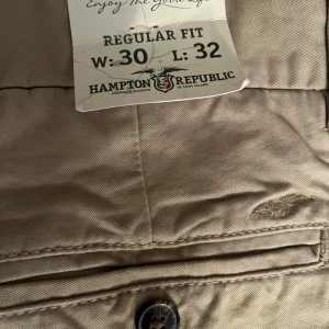 Beige byxor från Hampton Republic - Snygga beige byxor från Hampton Republic i regular fit. De har en klassisk design med knapp och dragkedja framtill. Perfekta för en stilren look.