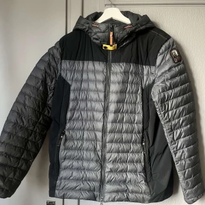 Grå och svart pufferjacka från Parajumpers - Säljer en snygg grå och svart pufferjacka från Parajumpers med huva och dragkedja. Kvitto och allt sådan finns. Äkta vara