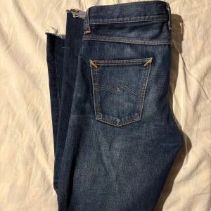 Blå jeans från Nudie Jeans - Snygga blå jeans från Nudie Jeans. Jeansen har en rak passform. Avklippta längst ner men påverkar inte storleken