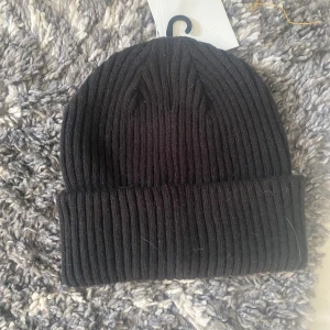 Svart ribbad mössa - Helt o använd Snygg svart ribbad mössa perfekt för kyliga dagar. Den är stilren och enkel att matcha med olika outfits. Passar både för höst och vinter.