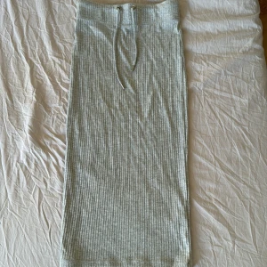 Grå ribbad kjol från Gina Tricot - Snygg grå ribbad kjol från Gina Tricot med knytband i midjan. Den är i en längre modell och aldrig använd💕