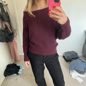 Vinröd stickad offshoulder-tröja - Säljer en mysig vinröd stickad tröja med offshoulder-design. Tröjan har långa ärmar och en avslappnad passform, perfekt för kyligare dagar. Den är både stilren och bekväm, ett måste i garderoben!