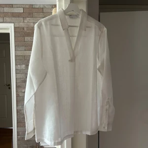 skjorta i overhead-modell - Vit skimrande skjorta i avslappnad passform, veck framtill och textur