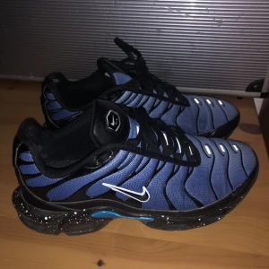 Nike tn sneakers i blått och svart - Snygga Nike sneakers i blått och svart med vita detaljer. Skorna har ett unikt mönster och snörning. Sulan är svart med vita prickar och har en cool design undertill.