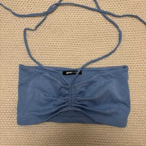 Blå tubtopp från Gina Tricot - Snygg blå tubtopp från Gina Tricot med knytband och rynkdetalj framtill. Perfekt för sommardagar och festivaler. Säljer för 34kr