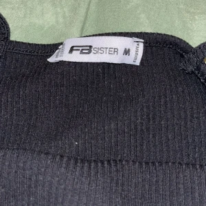 Svart ribbad linnetopp  - Snygg svart ribbad linnetopp från FB Sister med smala axelband. Perfekt för en stilren look. Passar bra till både jeans och kjol.