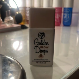 Golden Glow Drops från W7 - Golden Glow Drops från W7 är flytande bronzingdroppar som ger en strålande och solkysst look. Perfekt för att blanda med foundation eller använda direkt på huden för extra lyster.