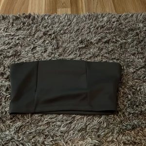 Svart tubtopp - Snygg och enkel svart tubtopp perfekt för olika tillfällen. Den är stilren och kan enkelt matchas med andra plagg för en trendig look. Från nakd 
