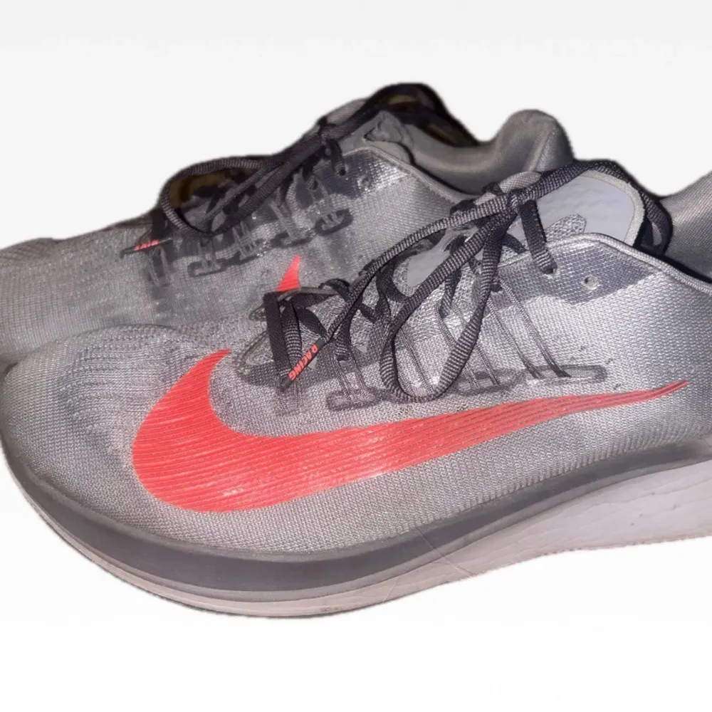 Snygga grå Nike löparskor med en iögonfallande röd swoosh. Skorna har snörning och en bekväm passform, perfekta för löpning och träning. Den grå färgen kombineras med en röd detalj för en sportig look. Ny pris: 3000kr. Kengät.