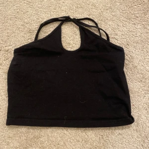 Svart halterneck topp från Shein - Snygg svart halterneck topp från Shein med smala axelband och öppen rygg. Perfekt för en stilren look.