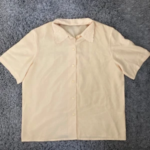 Pastellgul kortärmad skjorta/blus med broderi - Ljusgul loose fit kortärmad skjorta/blus med broderad krage från 80-talet. Toppen är inköpt på Beyond retro och är i gott skick. Passar strl S-L beroende på hur tight man vill ha den. Klicka gärna på köp nu och meddela för eventuella frågor. :)
