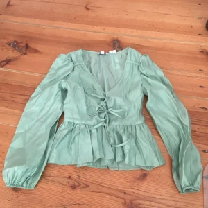 Grön blus med knytningar - En söt grön blus, men knytningar i fram. Det är 3 snören som man kan knyta hur man vill. Den är från Topshop.