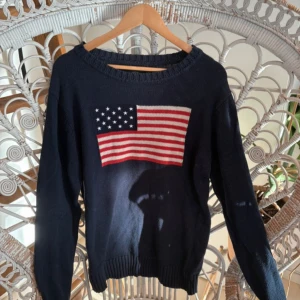Mörkblå stickad USA tröja  - ❤️ Säljer en trendig mörkblå stickad tröja från Crocker med USA föaggan på framsidan. Tröjan har långa ärmar och är tillverkad i en bomulls- och akrylblandning. ❤️