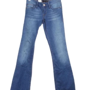 Blå bootcut jeans från Mavi - Snygga blå bootcut jeans från Mavi med klassisk femficksdesign och knappgylf. Perfekta för en avslappnad stil med en touch av retro. Märkesdetaljer på baksidan och etikett framtill.MÅTT-innerbenslängd 97 midjemått runt hela 68