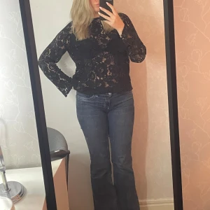 Svart spetsblus med öppen rygg - Säljer en svart spetsblus med långa ärmar och en vacker öppen ryggdetalj. Blusen har ett knytband i nacken. Använd bara 2 gånger.