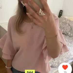 Rosa blus med volangärmar - Säljer en söt rosa blus med volangärmar. Perfekt för en feminin och stilren look. Blusen har en rund hals och är i en mjuk rosa nyans.💞