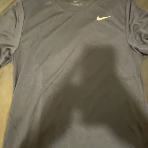 Blå träningströja från Nike - Snygg blå shirt från Nike med korta ärmar och klassisk passform. Perfekt för träning eller vardagsbruk med den ikoniska Nike-loggan på bröstet. Helt ny!