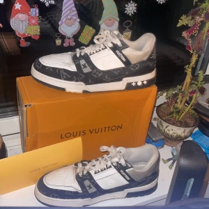 Svartvita sneakers från Louis Vuitton - Snygga svartvita sneakers från Louis Vuitton med monogrammönster. Skorna har snörning och en stilren design med märkets logotyp på sidan. Perfekta för den som vill ha en lyxig touch i vardagen. Byten e intressanta! Fler bilder kan skickas🔛🔝