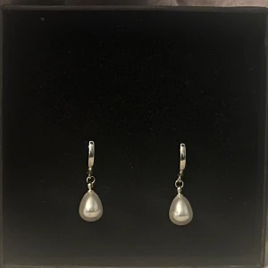 Silverörhängen  - Eleganta silverörhängen med droppformade pärlor. Perfekta för att ge en klassisk touch till din stil. Lätta att bära och passar till många tillfällen. Rostfritt stål