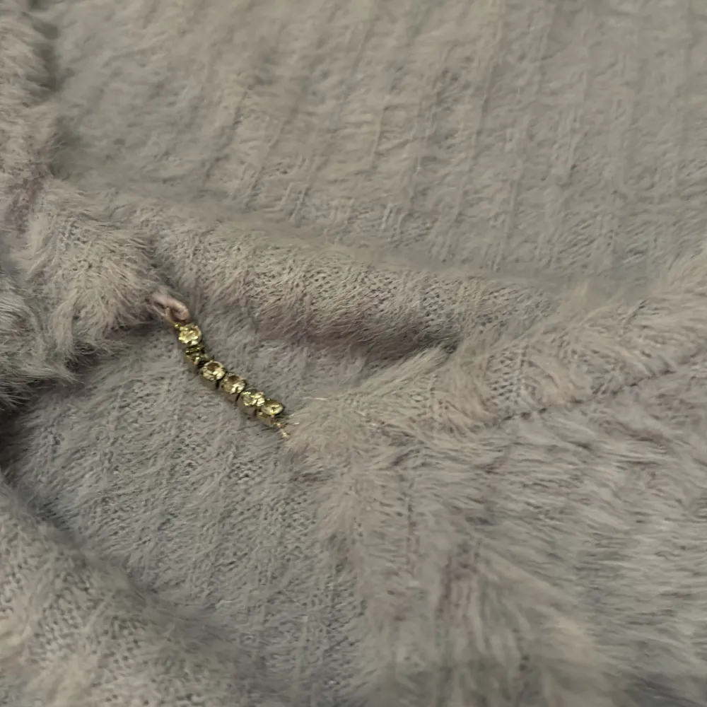 Mysig ljuslila kofta från FB Sister med en fluffig textur och ribbade detaljer. Koftan har långa ärmar och en dekorativ knäppning framtill med glittrande stenar. Perfekt för kyliga dagar!. Neuletakit & Villapaidat.