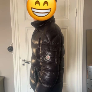 Svart pufferjacka från Moncler - Säljer en snygg svart pufferjacka från Moncler. Jackan har en glansig finish och är utrustad med dragkedja och hög krage. Perfekt för kyliga dagar.
