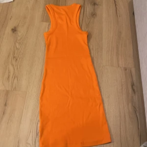 Orange ribbad klänning från Bik Bok - Snygg orange ribbad klänning från Bik Bok i storlek XS. Klänningen är ärmlös och har en tight passform som framhäver figuren. Perfekt för sommarens varma dagar! Priset kan diskuteras! 