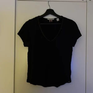 Svart t-shirt från Scotch & Soda - Snygg svart t-shirt från Scotch & Soda med v-ringning. Perfekt för en stilren look. Passar bra till både jeans och kjol.