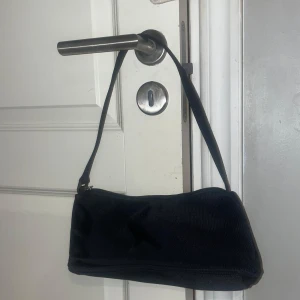 (HELT NY) Svart axelväska med dragkedja - Snygg svart axelväska i syntetmaterial med praktisk dragkedja. Perfekt för att bära dina nödvändigheter med stil. Enkel och elegant design som passar till många tillfällen.