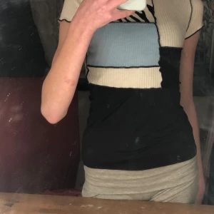 Randig ribbad topp i flera färger - Trendig kortärmad topp med ett unikt mönster i svart, vitt och blått. Toppen har en ribbad struktur och en cool zebra-detalj. Perfekt för att ge din outfit en edgy touch.