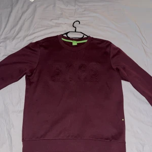 Vinröd tröja från Hugo Boss - Snygg vinröd tröja från Hugo Boss med subtilt märke på bröstet. 