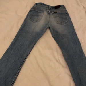 Blå jeans från Lee - Snygga blå jeans från Lee med klassisk femficksdesign. De har en bootcut passform och är tillverkade i slitstarkt denim. Perfekta för en avslappnad stil. Är i storlek s/m❣️