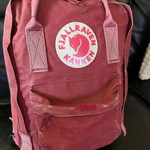 Röd Mini Kånken ryggsäck från Fjällräven - Säljer en röd Mini Kånken ryggsäck från Fjällräven. Den har justerbara axelremmar och en praktisk dragkedja framtill. Perfekt för vardagsbruk eller utflykter. 👜