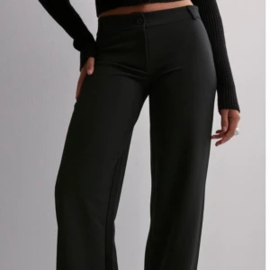 Svarta byxor från Nelly - Snygga svarta byxor från Nelly i storlek S.(lånade bilder)  De har en elegant wide passform och är perfekta för en stilren look. Byxorna är lågmidjade och tillverkade i ett bekvämt material. Säljs då dom inte kommer till användning. Pris kan diskuteras. Skriv om du har frågor🩷