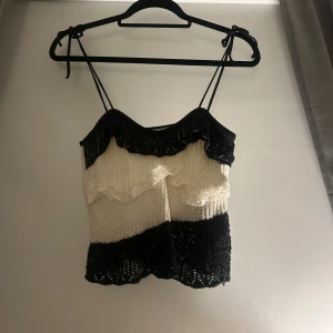 Svart och vit stickad linnetopp - Trendig stickad linnetopp i svart och vitt med smala axelband och volangdetaljer. Perfekt för en nyårs look med en unik design. Trendigt linne från zara.
