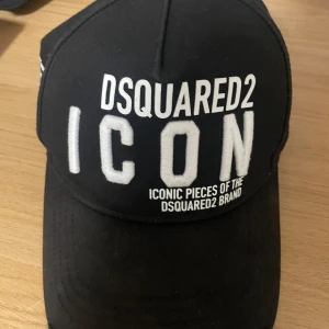 Svart keps från Dsquared2 - Snygg svart keps från Dsquared2 med vit broderad text 'ICON' framtill och märkesnamnet baktill. Perfekt för en stilren look. Kan ej köpas längre i butik!!