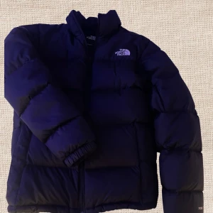 Svart dunjacka från The North Face - Säljer en svart dunjacka från The North Face. Jackan  är Perfekt för kalla dagar med sin varma och bekväma passform. Köpte den för cirka 3600kr i 2023, Dock har den 2 små hål där back men jag har försökt sy det och jag är väldigt dålig på sy.