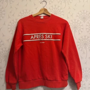 Röd sweatshirt med 'Après Ski' tryck - Säljer en röd sweatshirt med texten 'Après Ski' tryckt på framsidan. Tröjan har långa ärmar och en rund halsringning. Perfekt för en avslappnad stil.