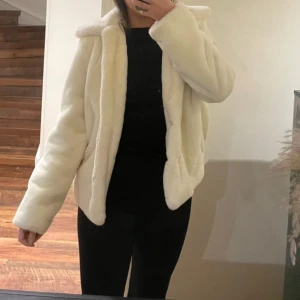 Vit pälsjacka  - Säljer en supermjuk och stilren vit pälsjacka. Jackan har en normal passform med långa ärmar och en mysig krage. Perfekt för att hålla sig varm och trendig under kyliga dagar. Knäppet på jackan har gått av som man kanske kan se på sista bilden. 