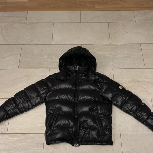 Svart dunjacka från Moncler - Hej, säljer min moncler jacka i stl 3 alltså M/L för att den inte passar helt enkelt. Jackan är i perfekt skick förutom att en knapp har lossnat vid luvan men såklart får man med original reserv knapp så det går att lösa smidigt och enkelt. Kvitto i fysiskt format och på mailen fås självklart med vid köp!  Nypris ca 18.000kr 