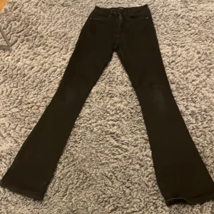 Svarta bootcut jeans från ONLY - Snygga svarta bootcut jeans från ONLY med hög midja och klassisk femficksdesign. Perfekta för en stilren look, dessa jeans har en dragkedja och knapp framtill.