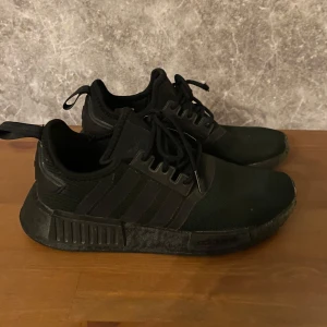 Svarta sneakers från Adidas - Säljer ett par svarta Adidas sneakers med snörning. Skorna har en stilren design med diskreta ränder på sidan och en bekväm sula. Perfekta för vardagsbruk.