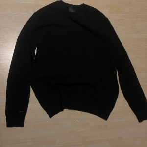 Svart stickad woffel tröja från H&M - Säljer en stilren svart stickad tröja från H&M. Tröjan har en klassisk design med rund hals och långa ärmar. Perfekt för kyligare dagar och enkel att matcha med olika outfits.