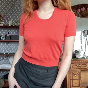 Röd/orange kortärmad topp - Röd/orange kortärmad topp med rund halsringning. Toppen har lite stretch och är tillverkad i mjuk bomull.  Längd: 49cm Bredd: 41cm Ärm: 18cm