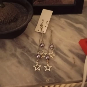 Långa örhängen med stjärnor och pärlor - Snygga långa örhängen med silverfärgade stjärnor och pärlor. Vet inte vart dom kommer ifrån, dom är använda en gång och sen har dom bara legat i mitt smyckeskrin. De har nå lite gult på sig men inget man ser. 