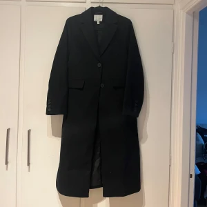 Svart kappa - Fin svart kappa med knappar framtill. Den är i princip aldrig använd! 