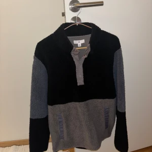 Svart och grå fleece från BP - Mysig fleece från BP i svart och grått. Tröjan har en halv dragkedja och hög krage, perfekt för kyliga dagar. Den är långärmad och har en avslappnad passform.