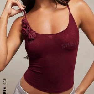 Vinröd linnetopp från Shein - Snygg vinröd linnetopp från Shein med smala axelband och dekorativa blommor på ena axeln. Perfekt för en stilren och trendig look. Aldrig använd och prislappen är kvar❤️