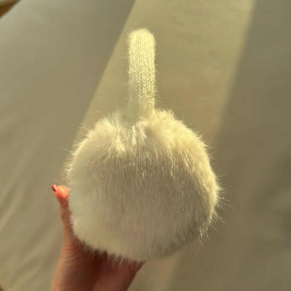 Snygga och varma vita öronmuffar med fluffig pälsimitation. Perfekta för kalla vinterdagar. De har en stickad bygel som ger en bekväm passform.. Asusteet.