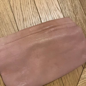 Rosa kuvertväska/necessär  från Acne Studios - Säljer en stilren rosa kuvertväska från Acne Studios. Väskan är tillverkad i ett mjukt material och har en enkel design utan extra detaljer. Perfekt för att bära med sig det nödvändigaste.